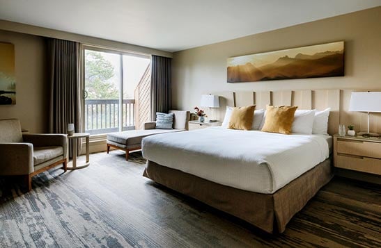 A hotel room with large bed with balcony doors.