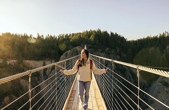 A woman stands on the skybridge with sunbeams coming from the left.