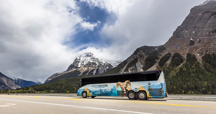 Brewster Sightseeing Bus driving down the highway past the mountains