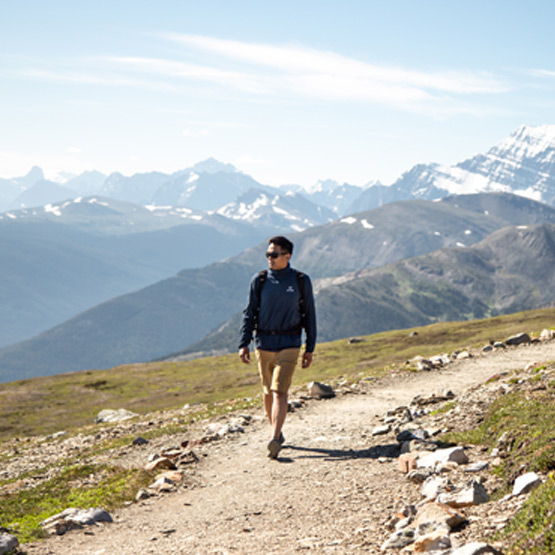 A hiker walking along a trail with a mountain view