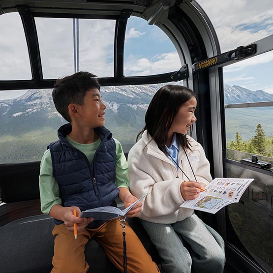 Two children in a gondola cabin with Rockies Rangers booklets.