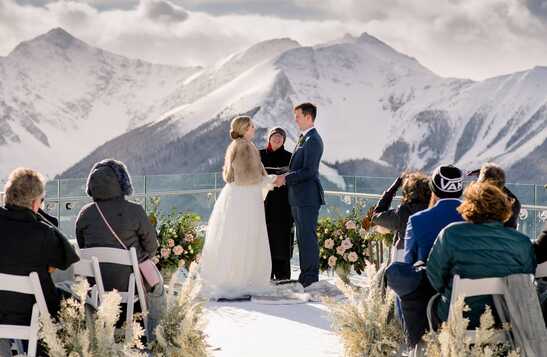 A group of people dressed for the winter smile in a Christmas-decorated place.