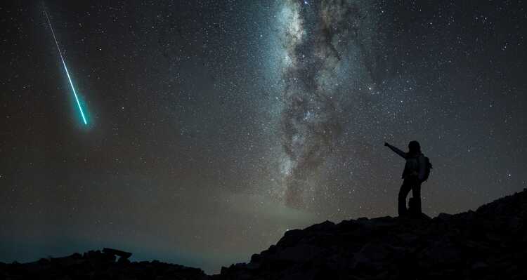 A person pointing at a meteor from the top of Whistlers Mountain