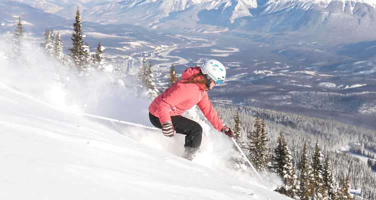 A person downhill skiing with Jasper village in the background