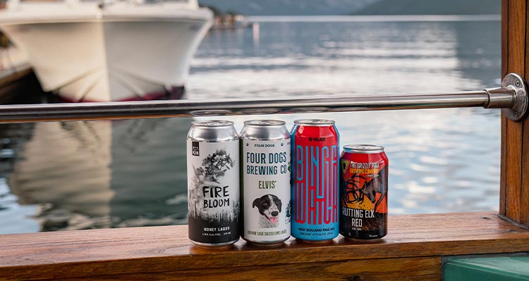 A set of beer cans on display against a boat window.