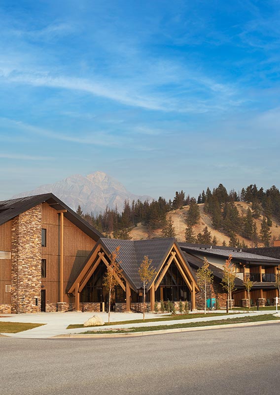 A hotel alongside an open road below forested mountains.