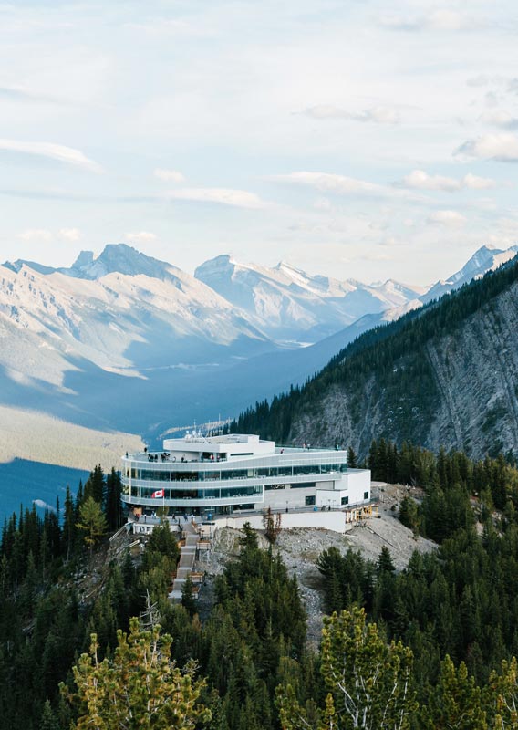 A summit building atop a forested and rocky mountain
