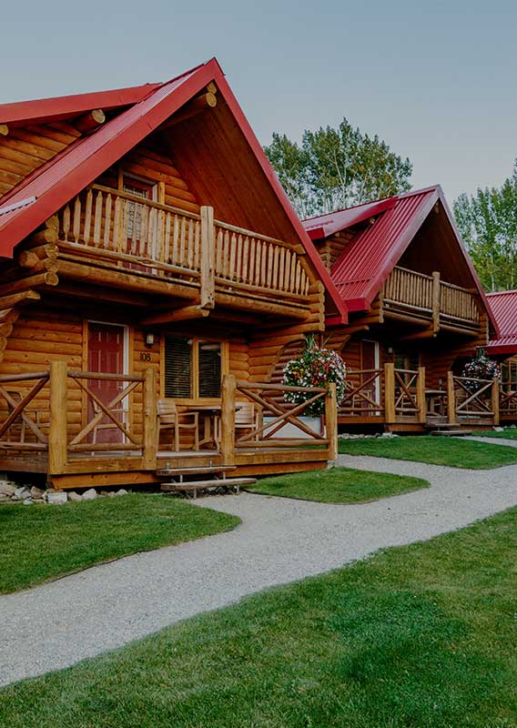 A series of wooden cabins with red roofs near a snowy forest