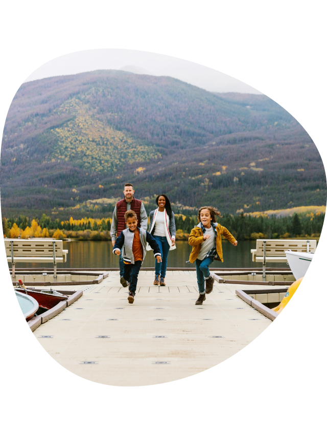 A family running down a lakeside dock.