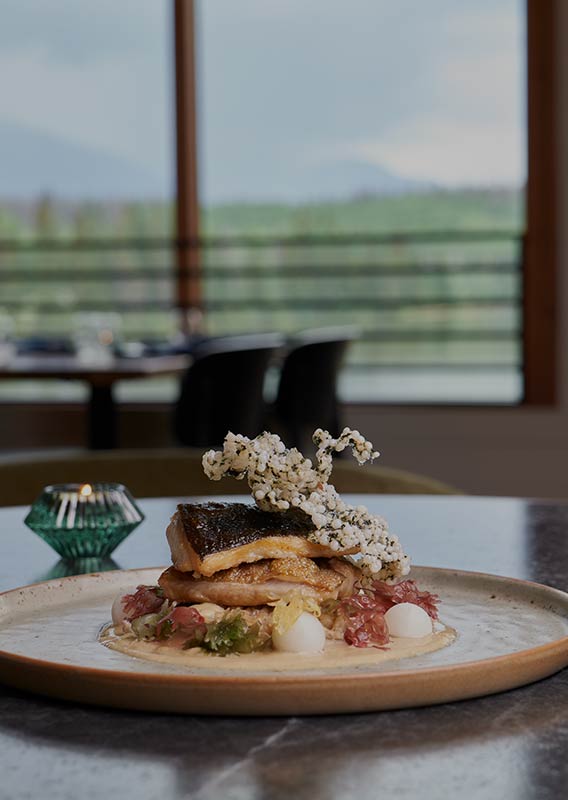 A dinner dish plated with a glass of white wine.