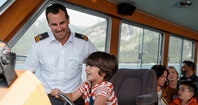 Male child steering under the guidance of the captain