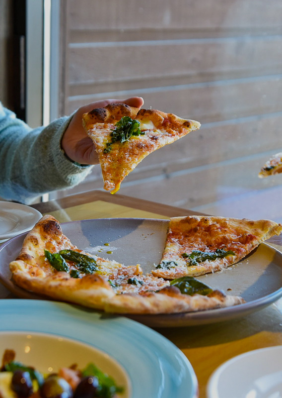 Two people eating pizza and drinking wine