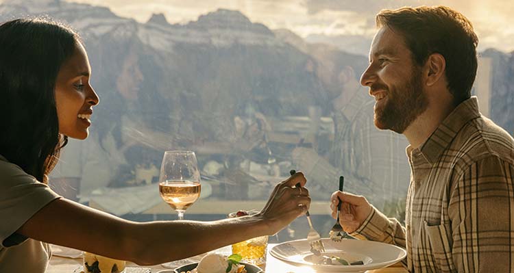Female and male sharing dinner with a view of the mountains in the background