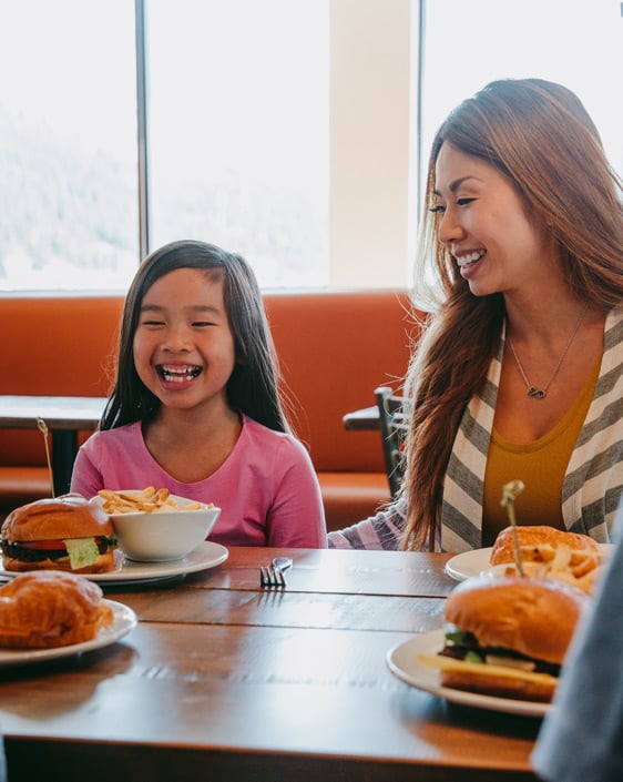 A parent and child laughing while dining at Chalet
