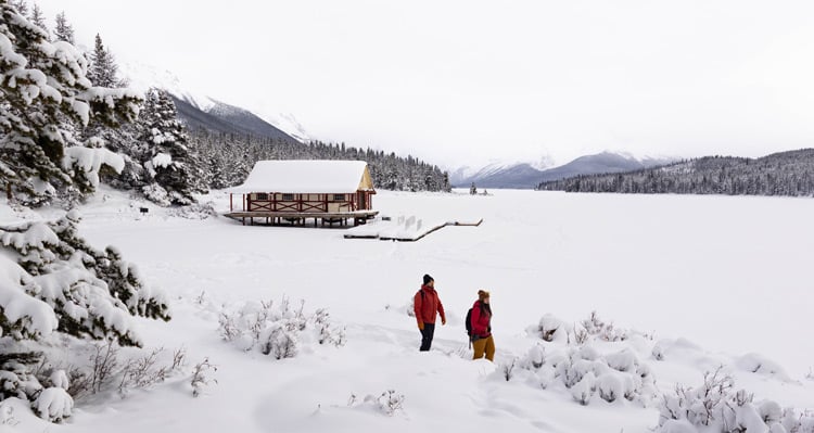 A couple walking along Mary Schaeffer Loop at Maligne Lake in the winter