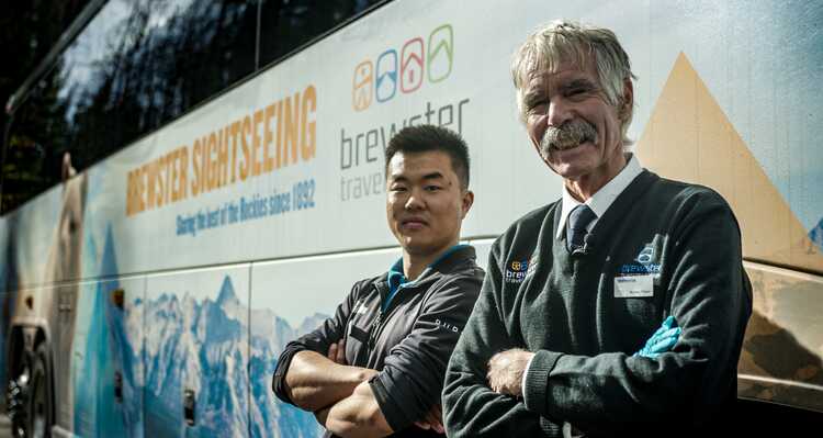 Two Brewster Sightseeing staff members posing in front of a Brewster Sightseeing bus.