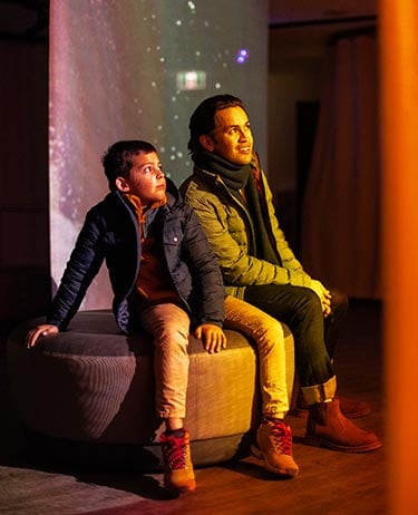Father and son sit inside Nightrise lights.