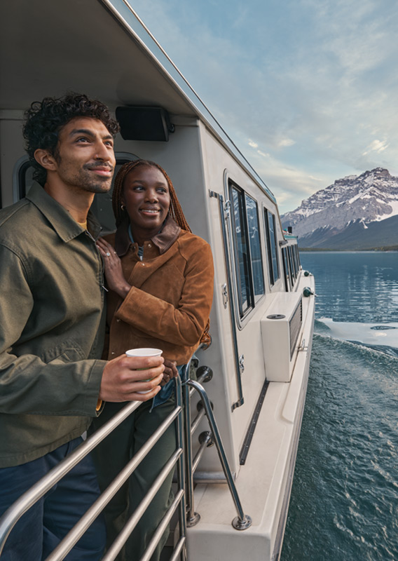 Two people looking at the mountain view from the Lake Minnwanka Premium Cruise.