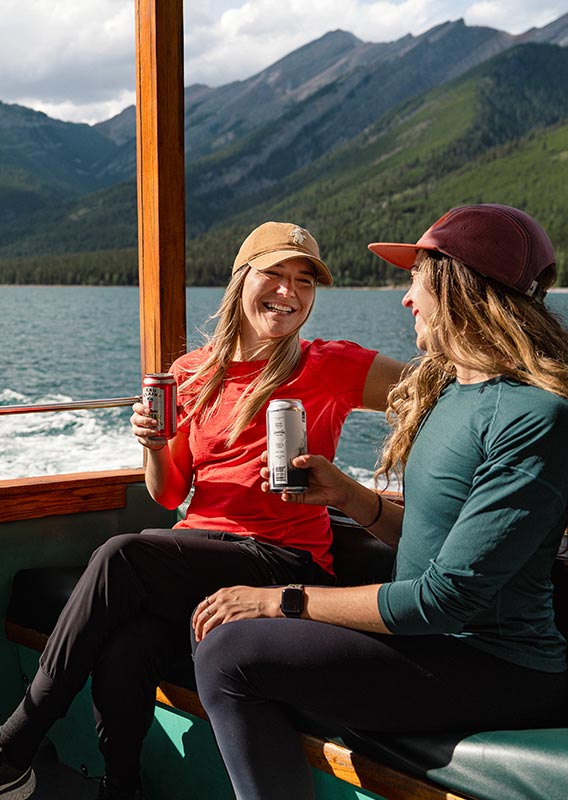 Two people relax at the back of a boat with beers.