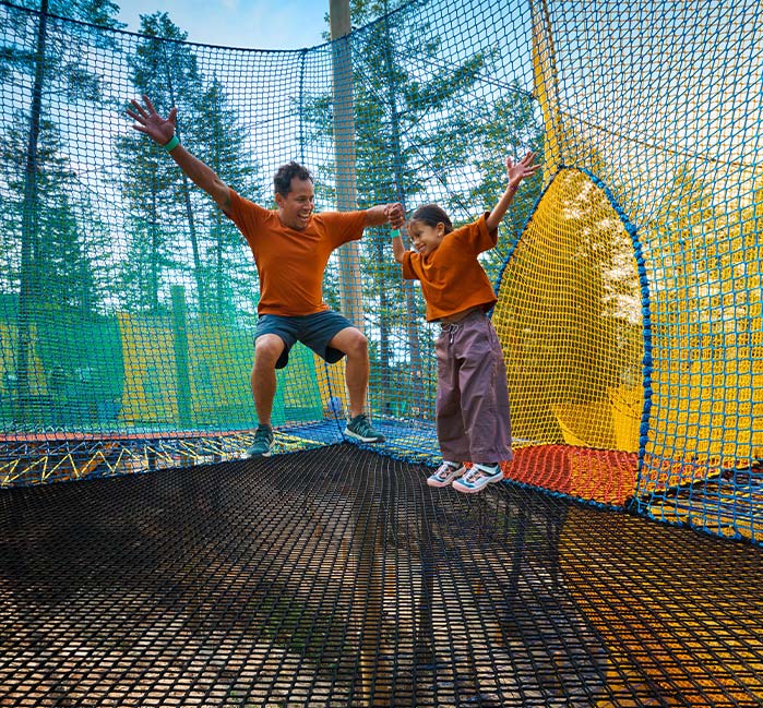 Four people bounce in a net park.