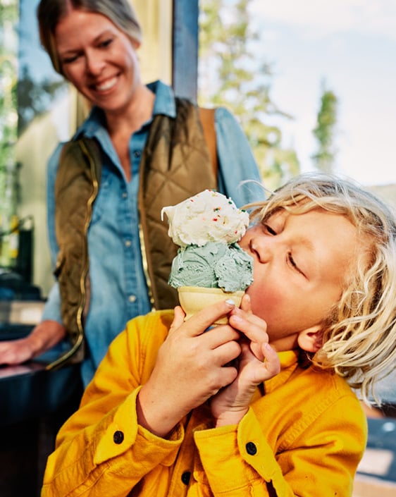 A parent smiling while watching their kid eat ice cream