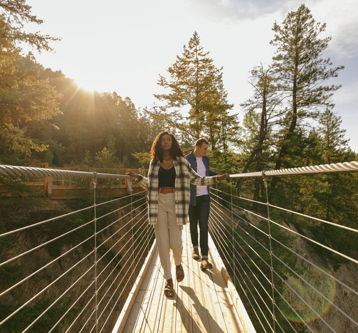 Two people walking across a suspension bridge at Golden Skybridge