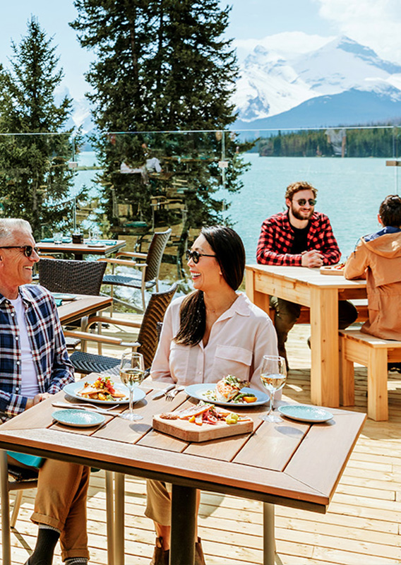 A group of friends sit on a patio enjoying food.