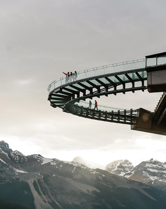 Upshot of a group standing on the Columbia Icefield Skywalk, pointing at the view of the mountains.