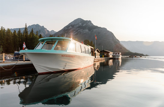 Lake Minnewanka Cruise boat docked on lake with mountain view