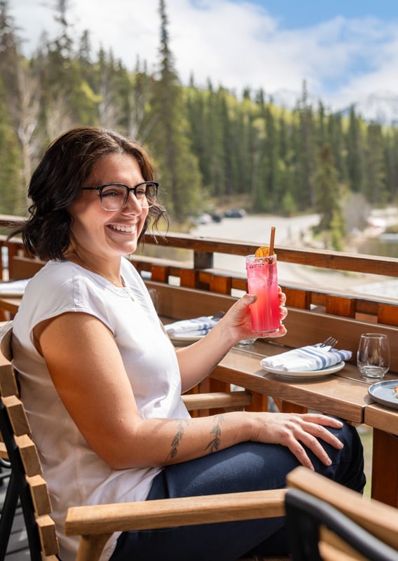 Friends dining at an outdoor patio by the water with a mountain view