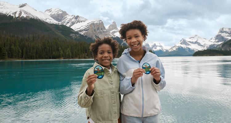 Two kids holding their Rockies Rangers badges at Maligne Lake.