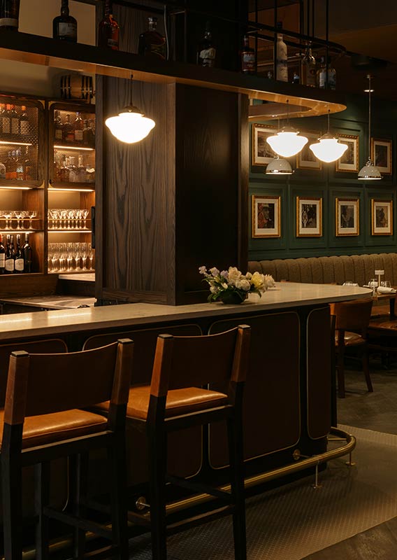 An empty bar with green chairs and white stone top.