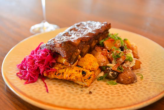 A dinner plate of ribs, corn and potato salad.