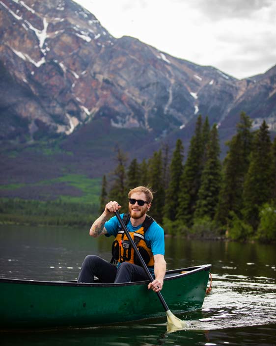 A person canoeing on a lake with a mountain view