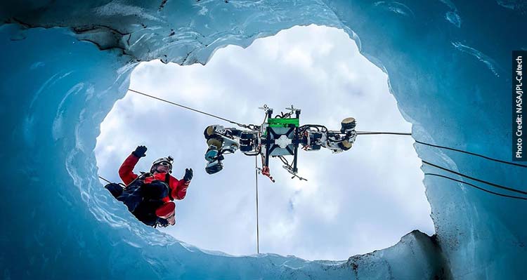 A shot from below of a research team lowering a robot into the Columbia Icefield.