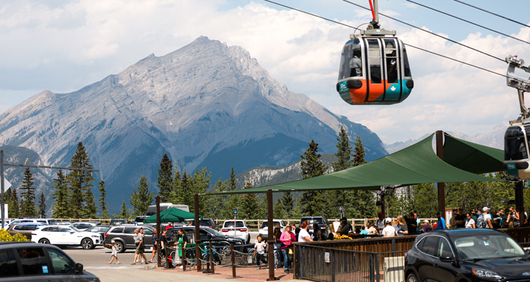 A Banff Gondola descending over the basecamp parking lot.