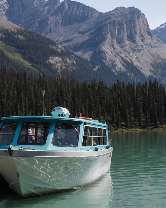 A boat docked on Maligne Lake with a mountain in the background