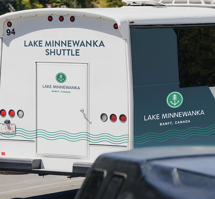 A small bus driving in a parking lot.