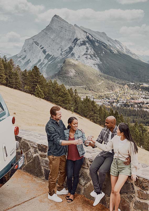A group of friends stop on Norquay Road and look out over the town of Banff.