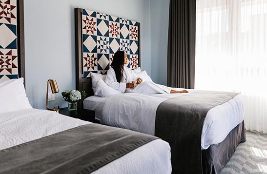 A woman sitting on a bed in Mount Royal Hotel.