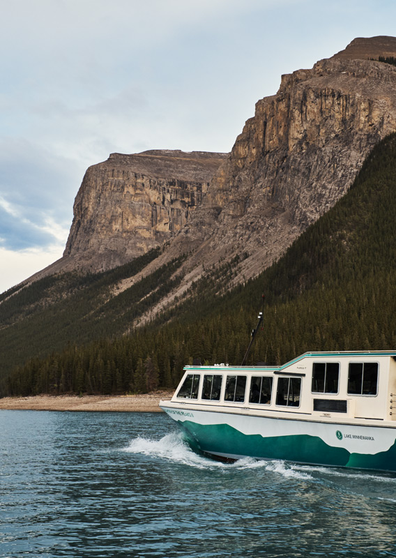 The Lake Minnewanka Premium Cruise sailing passed mountains during the tour.