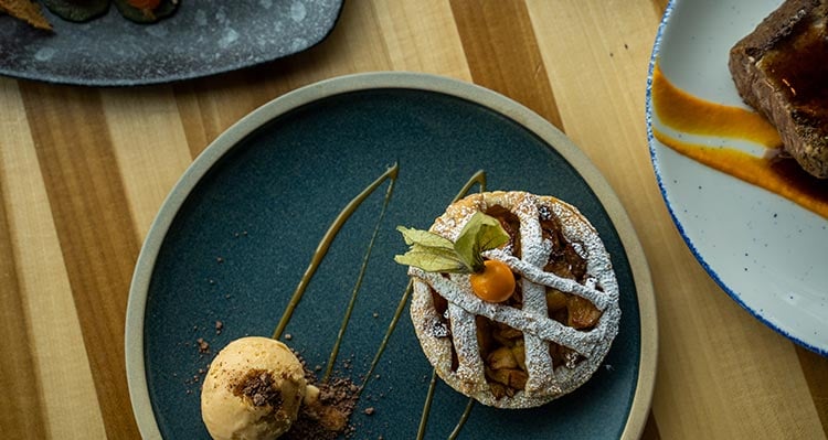 A dessert plate with a tart and ice cream scoop.