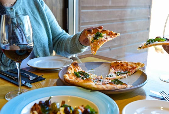 Two people lift slices of pizza up from a large plate.