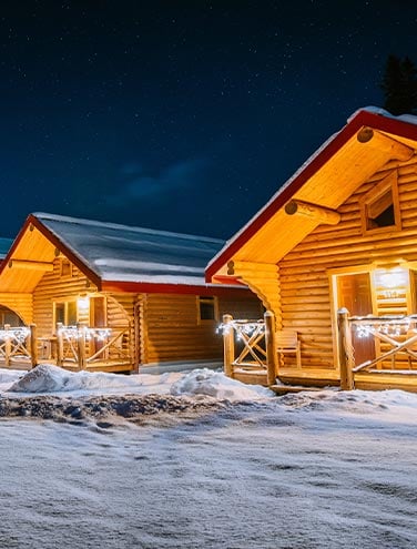 A row of cabins lit up at night in the winter