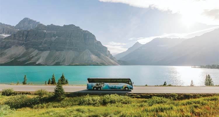 Brewster bus driving past a lake and mountains