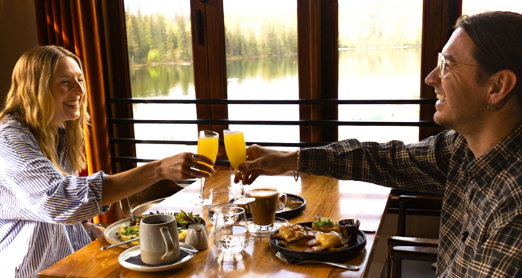 Two people toasting over breakfast at Aalto