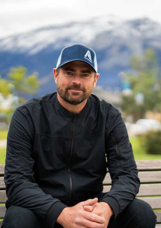 A portrait of Max Darrah, wearing a black jacket and blue hat.