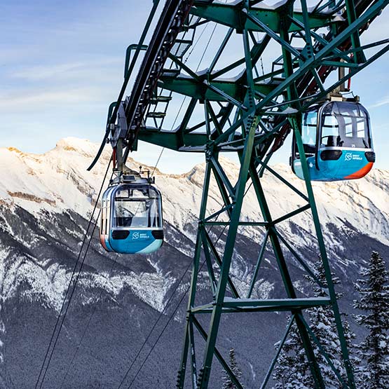 Two gondola cabins going up the mountain in winter.