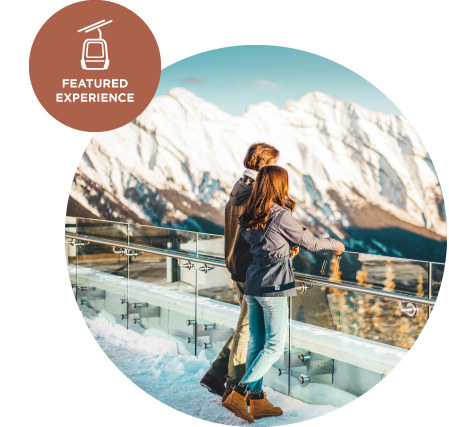 A man and woman stand at the Banff Gondola observation deck in winter.