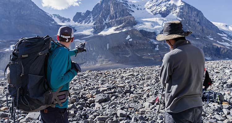 Two researchers on the Athabasca Glacier, pointing at a peak